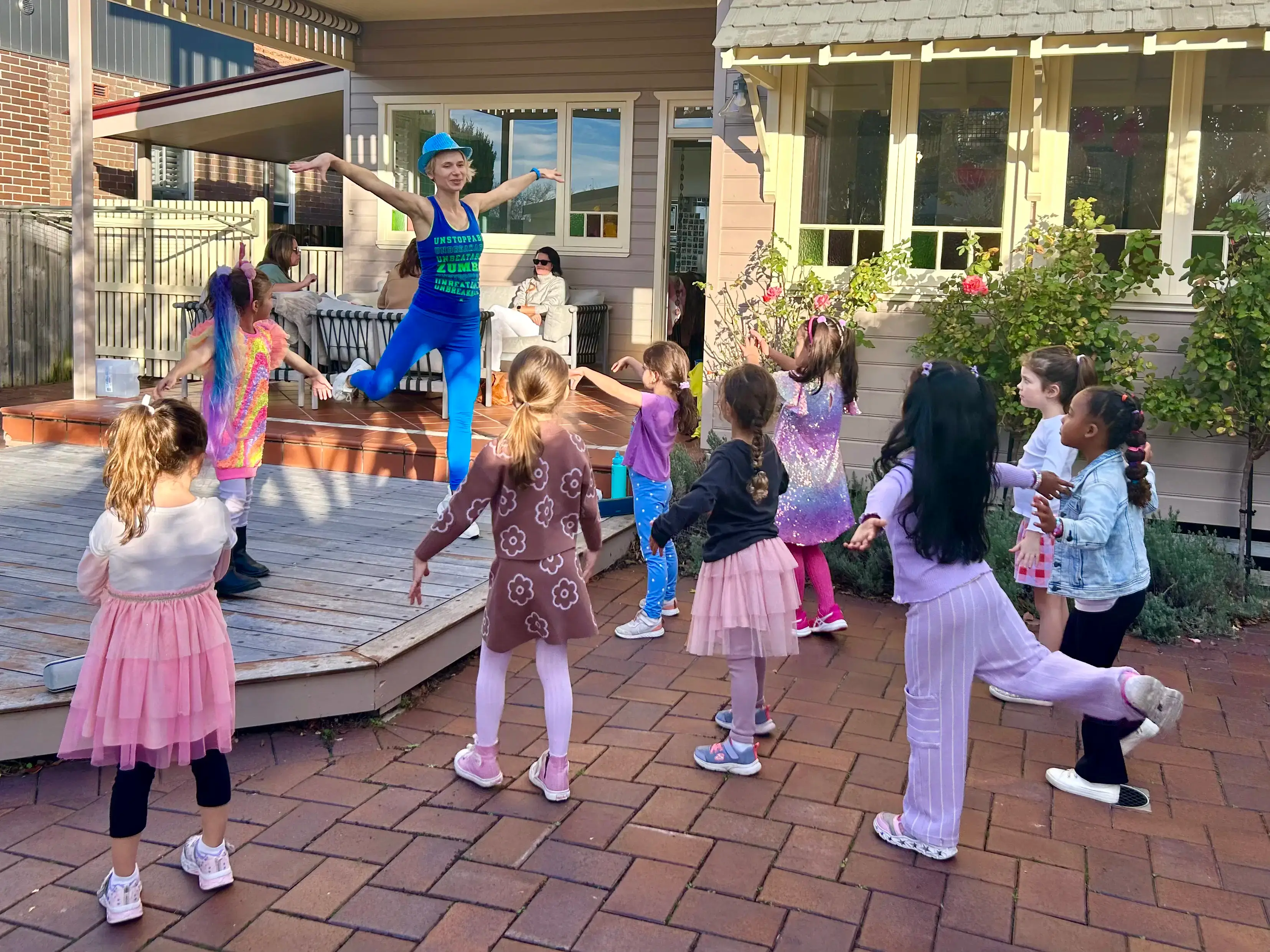 Professional dance party entertainer leading a circle of girls dancing on a backyard deck