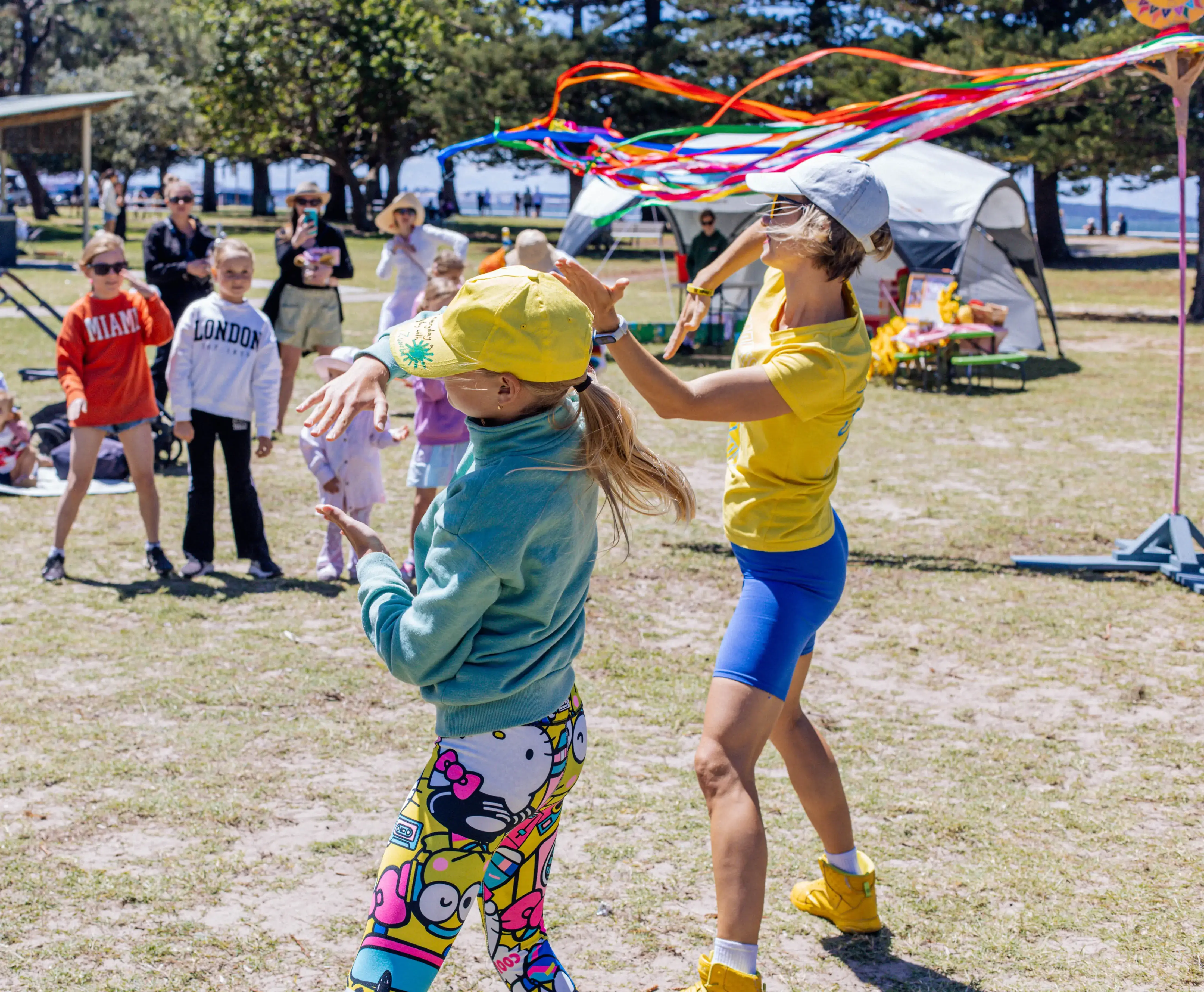 Professional dance party entertainer and a child swinging rainbow ribbons at an outdoor community family day