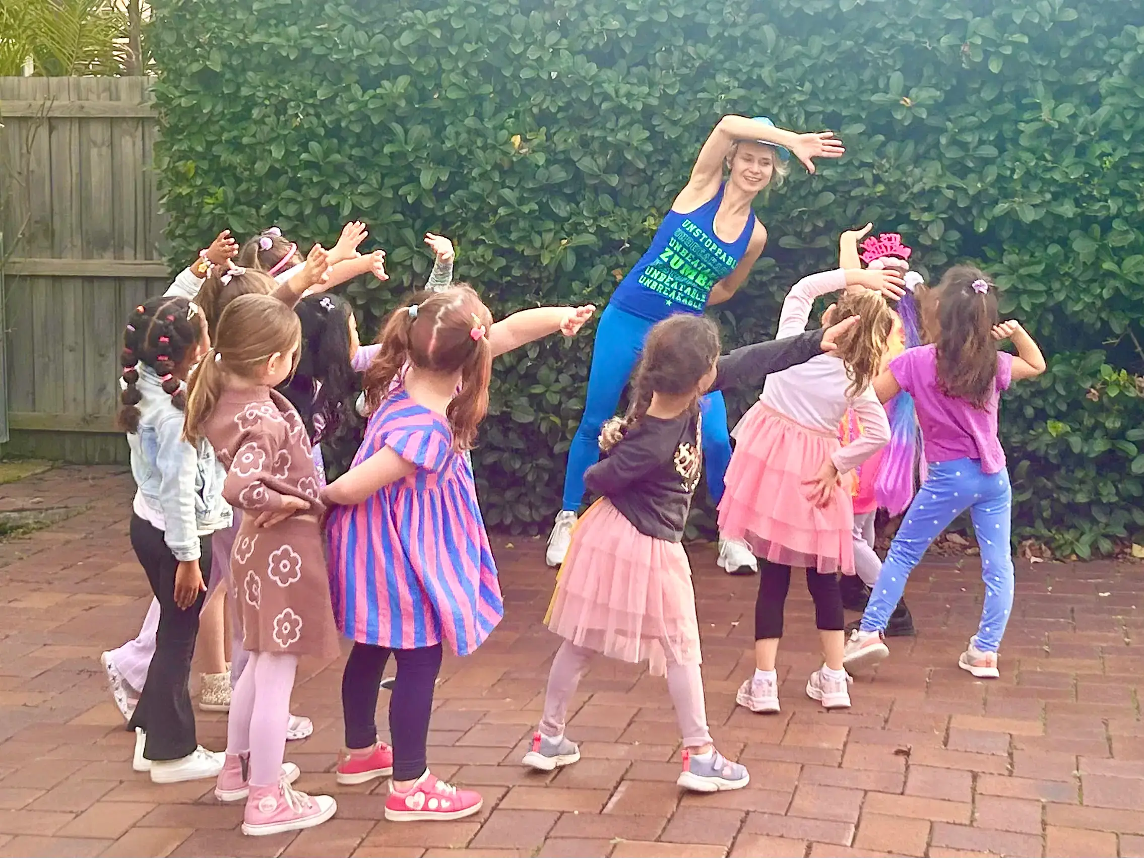 Professional dance party entertainer stretching with a group of girls in a backyard birthday party