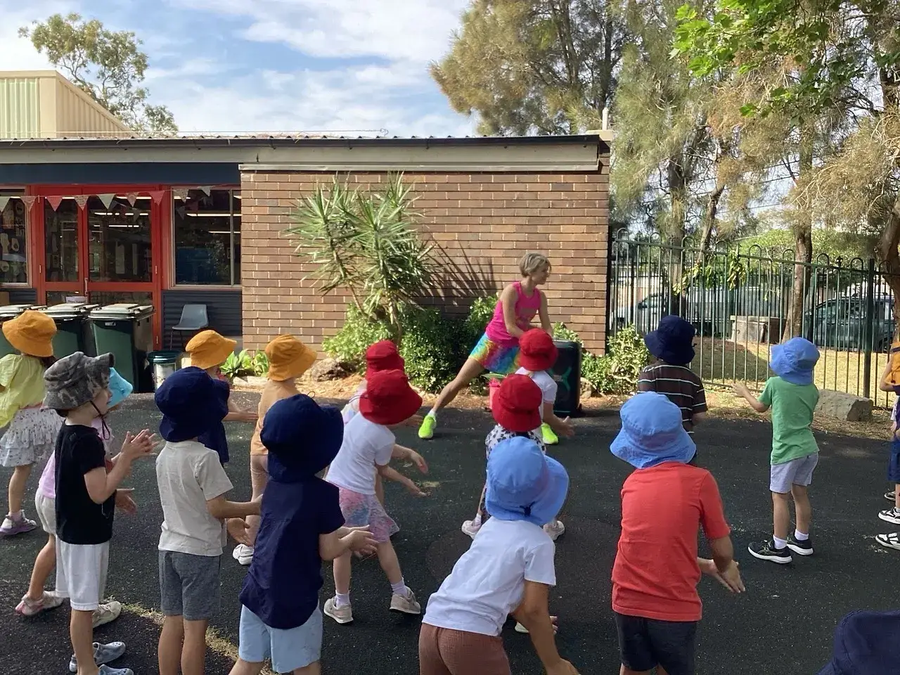 Preschoolers in sun hats dancing outdoors with the professional dance party entertainer
