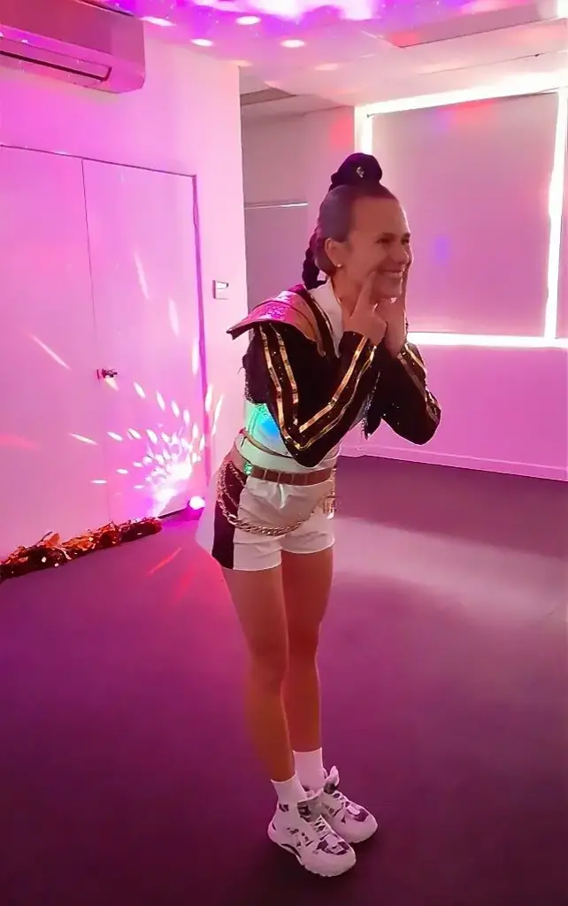 Professional dance party entertainer in K-Pop costume laughing in a room lit pink by party lights
