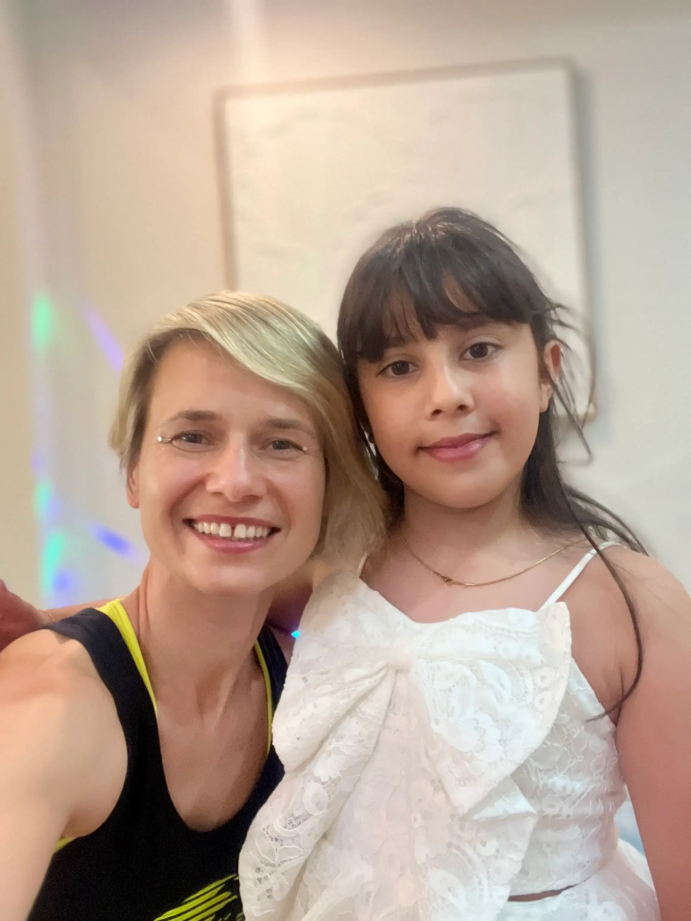Elena smiling in a selfie with a girl in a white party dress