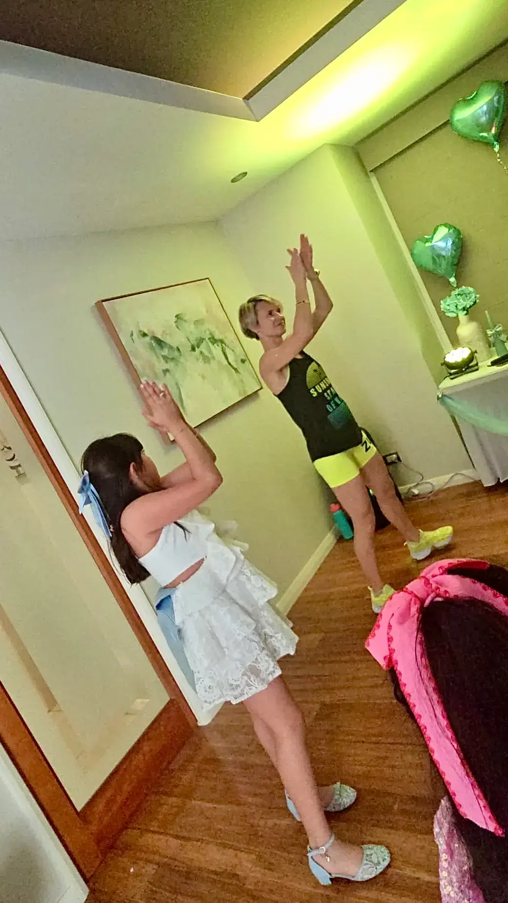 A girl copying the professional dance party entertainer's arm moves at a home party with heart balloons