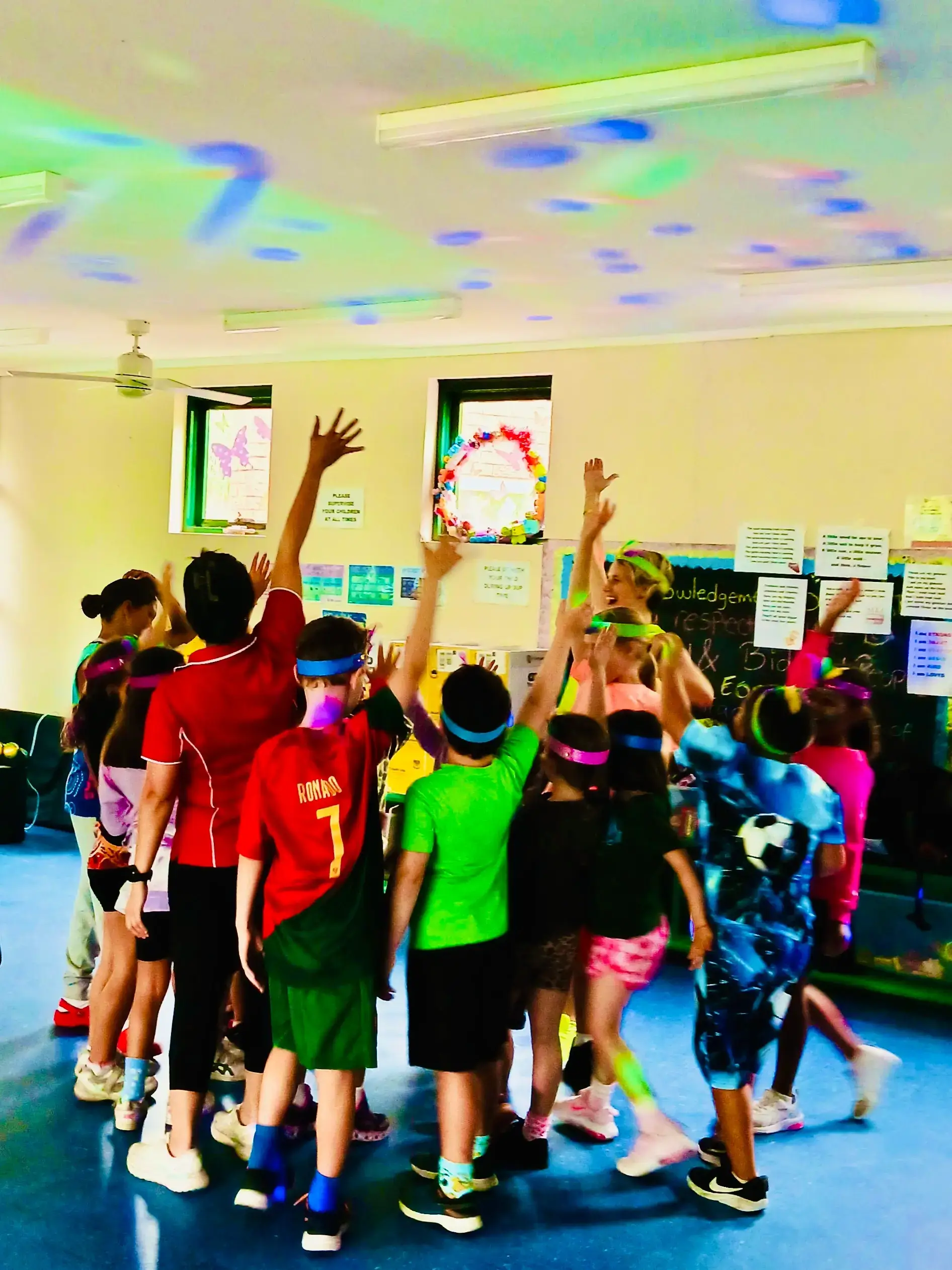 Children with their hands in the air dancing towards the professional dance party entertainer