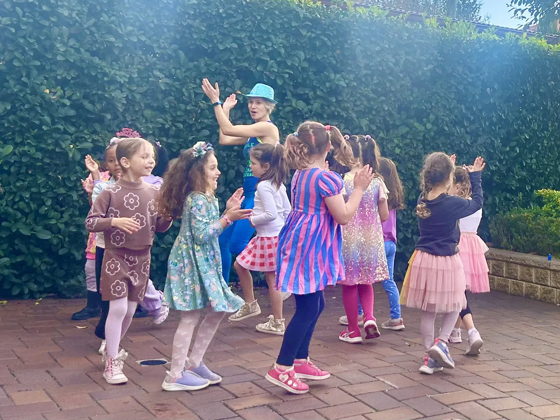 Children dancing in a circle with the professional dance party entertainer at a garden party